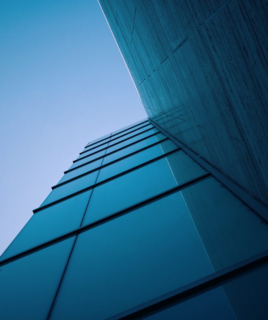 Glass office building corner against a blue sky