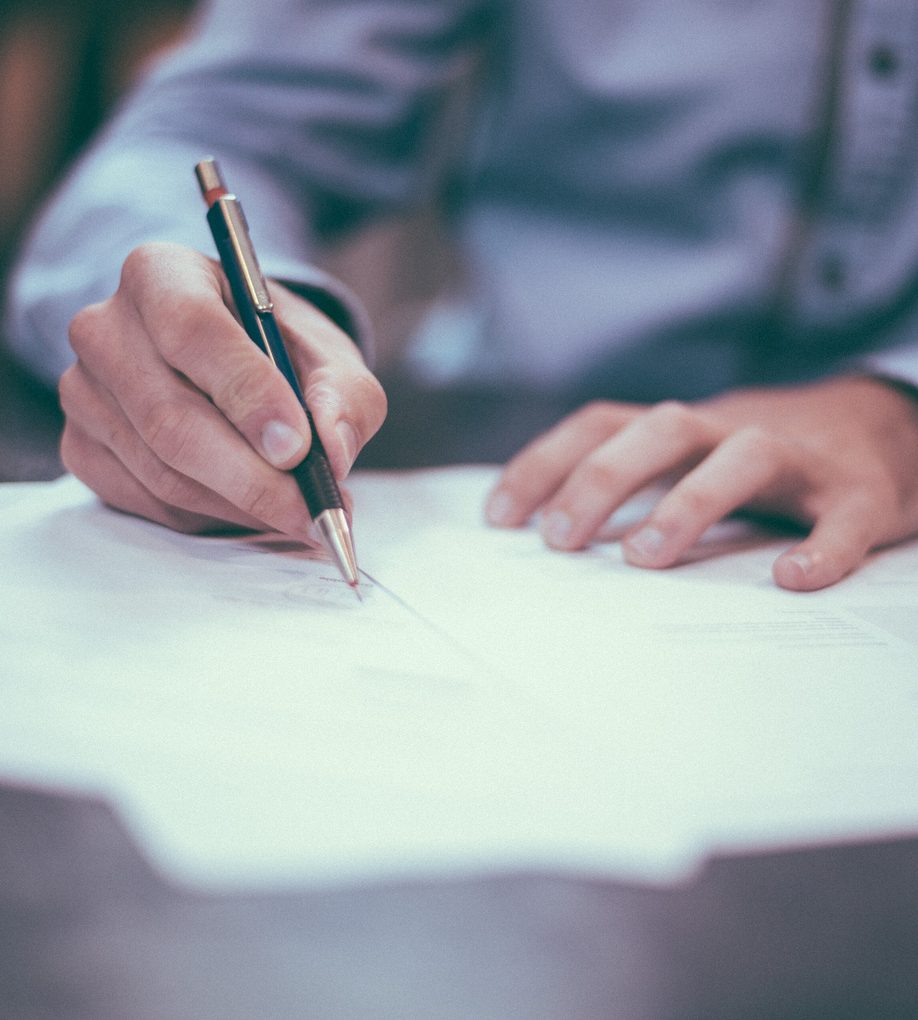Hands signing a printed agreement with a pen