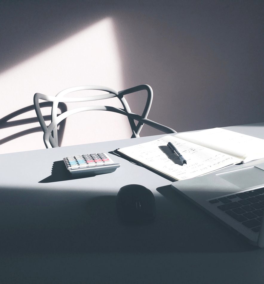 Calculator, notebook and pen on a sunlit desk